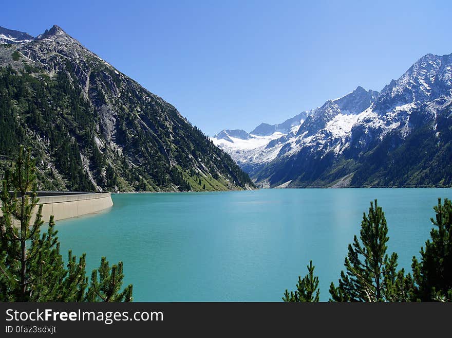 A hydroelectric dam water reservoir and mountains in the background. A hydroelectric dam water reservoir and mountains in the background.