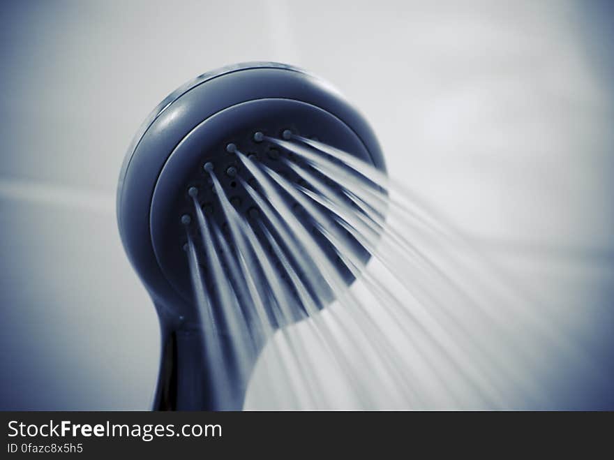 Close up a shower head spouting water.