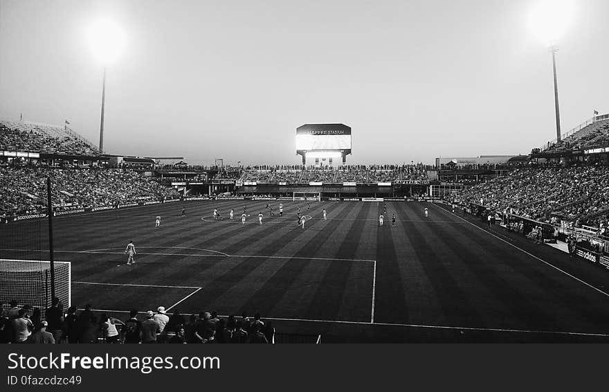 A black and white photo of a football stadium with an ongoing game.