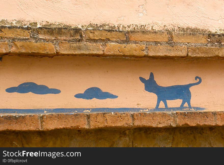 A cute cat painting on the wall of an old house.