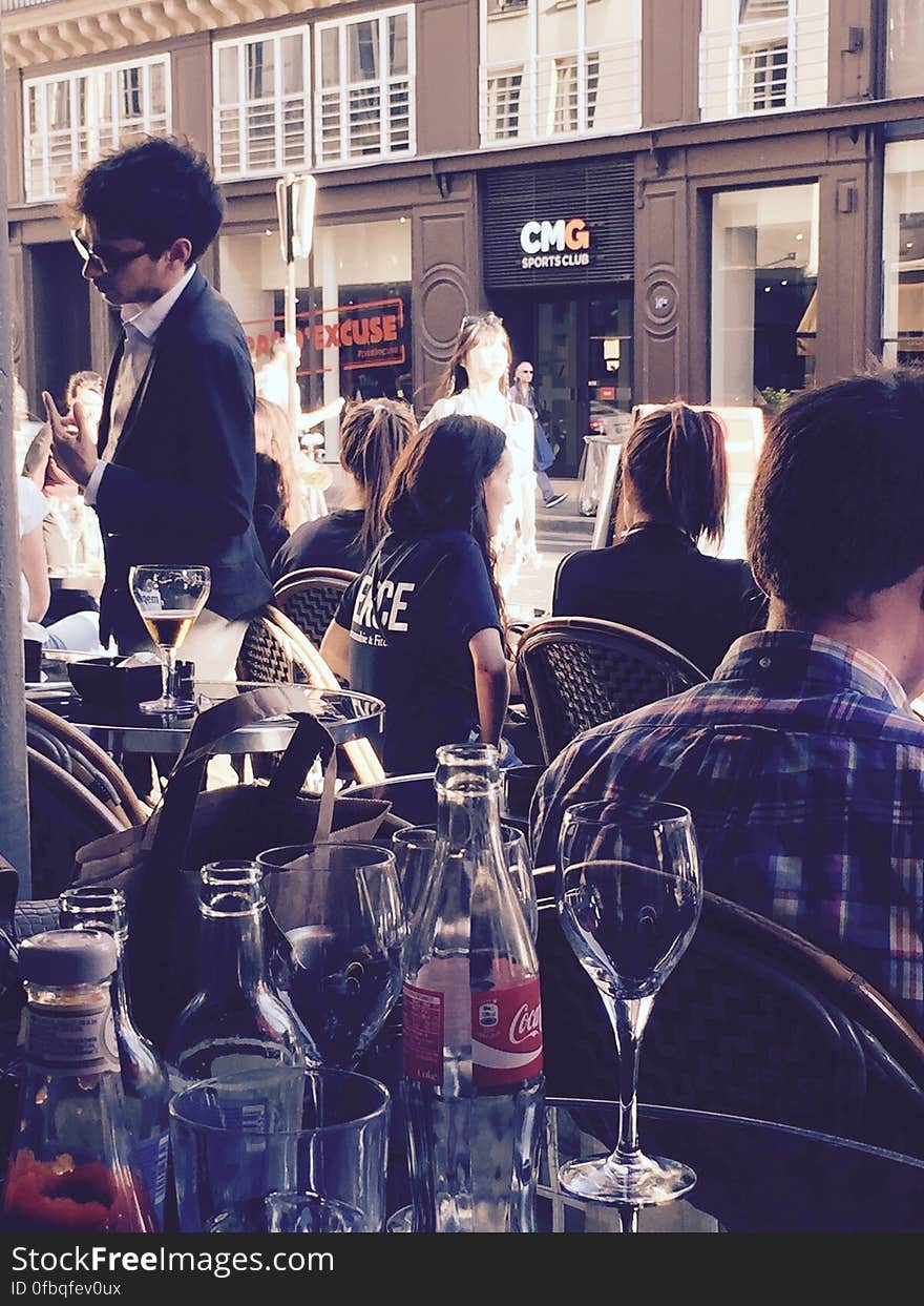 People sitting in an outdoor bar next to a pedestrian street. People sitting in an outdoor bar next to a pedestrian street.