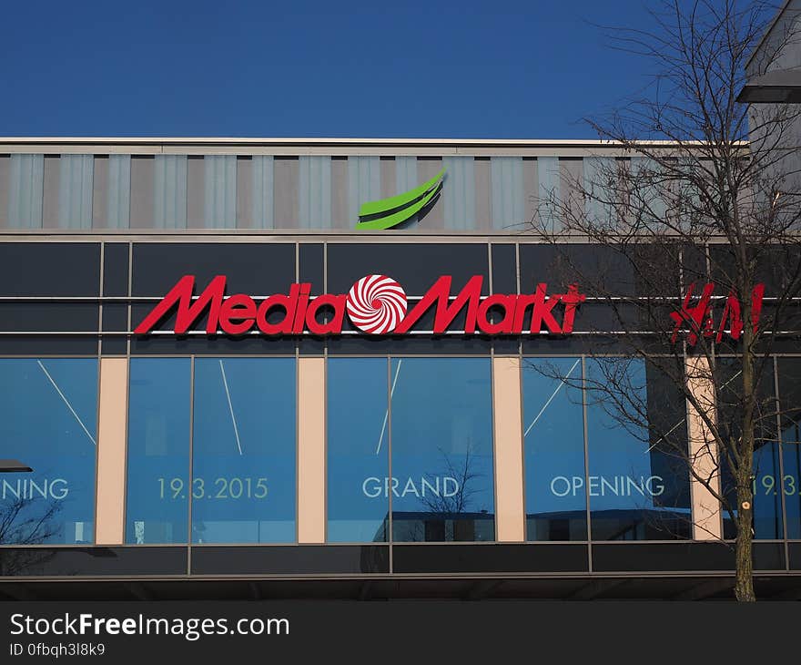 Media Markt logo and sign outside store with grand opening banner on sunny day. Media Markt logo and sign outside store with grand opening banner on sunny day.