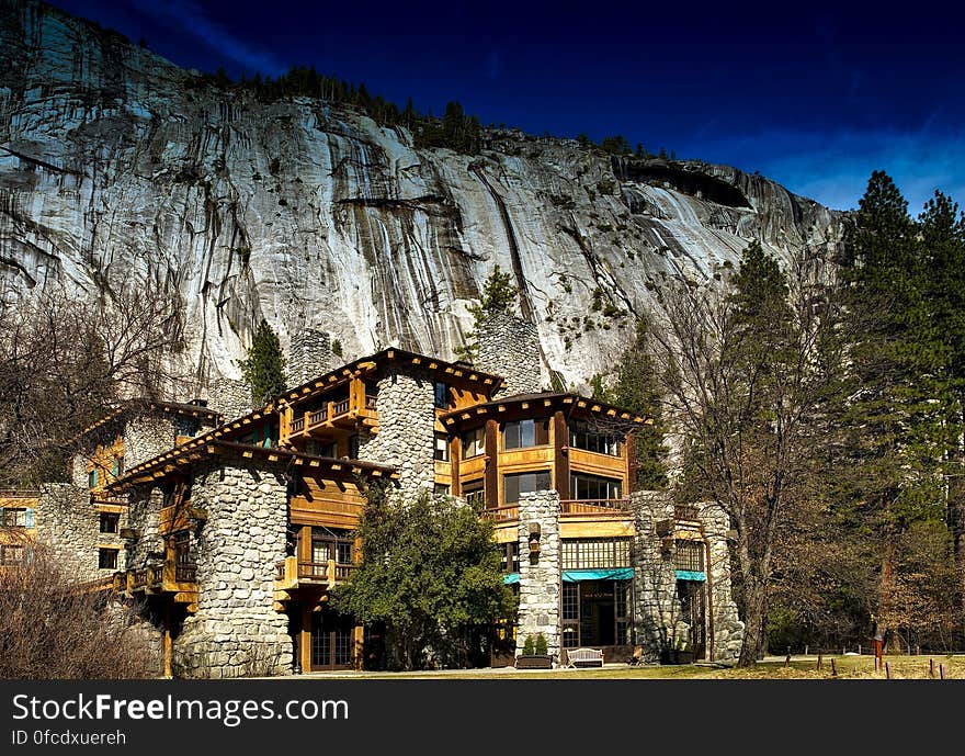 Rustic lodge in Yosemite National Park, California on sunny day against rocky cliff.