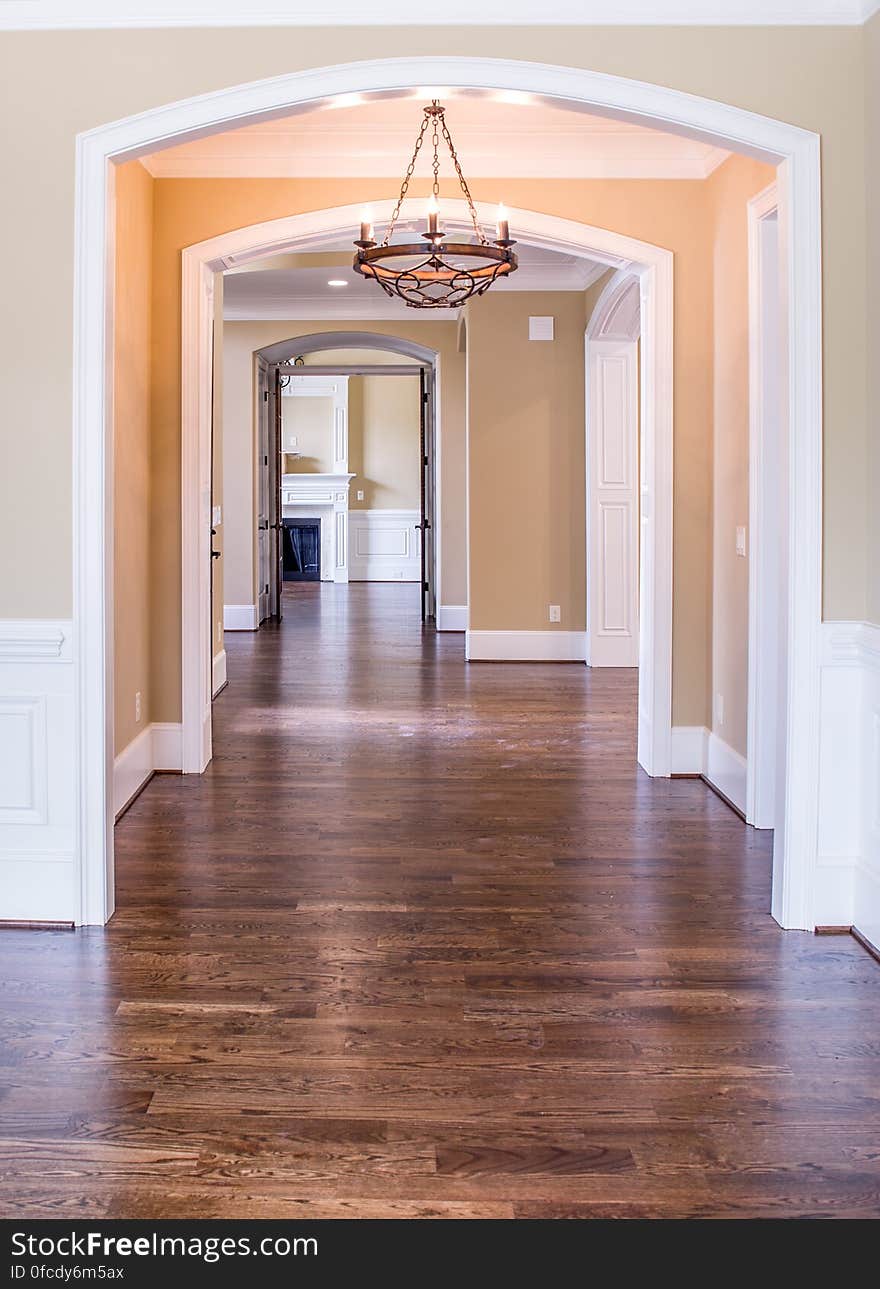 Empty hallway with wooden floor through arched doorway inside home. Empty hallway with wooden floor through arched doorway inside home.