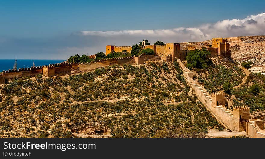 Fortress with stone wall on hillside overlooking waterfront on sunny day. Fortress with stone wall on hillside overlooking waterfront on sunny day.