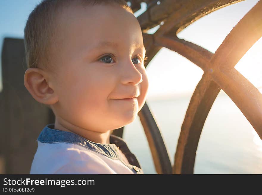 Portrait of smiling child standing next to sunny window.