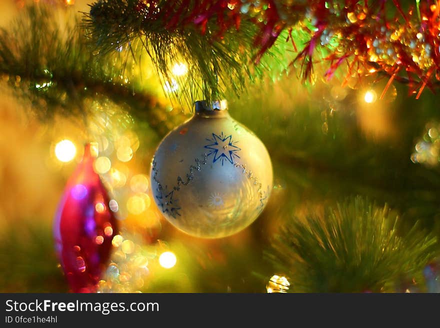 Close up of Christmas ornament on tree with lights.