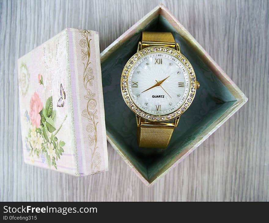 Vintage ornate gold wristwatch inside floral decorative box. Vintage ornate gold wristwatch inside floral decorative box.