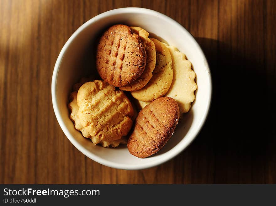 A close up of homemade biscuits in a bowl on a wooden table. A close up of homemade biscuits in a bowl on a wooden table.