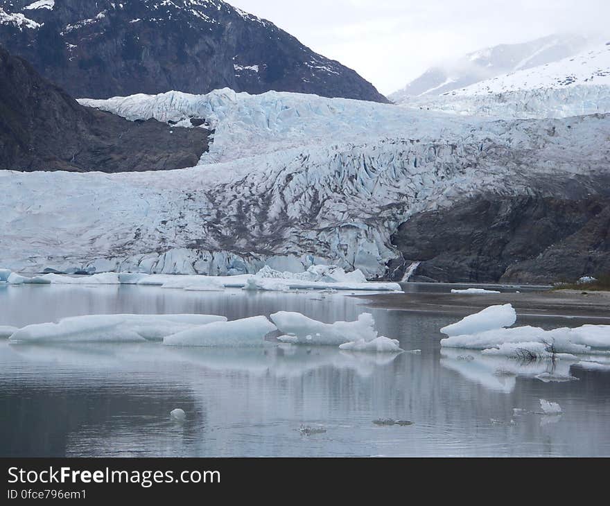 Arctic glacier and floating icebergs in the sea around.