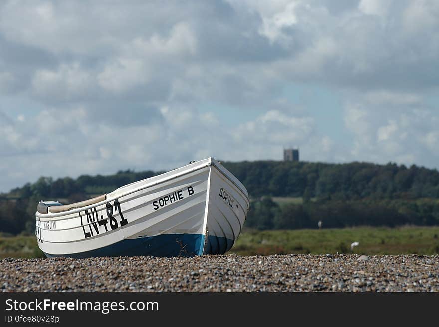 Wooden boat on rocky beach on sunny day. Wooden boat on rocky beach on sunny day.