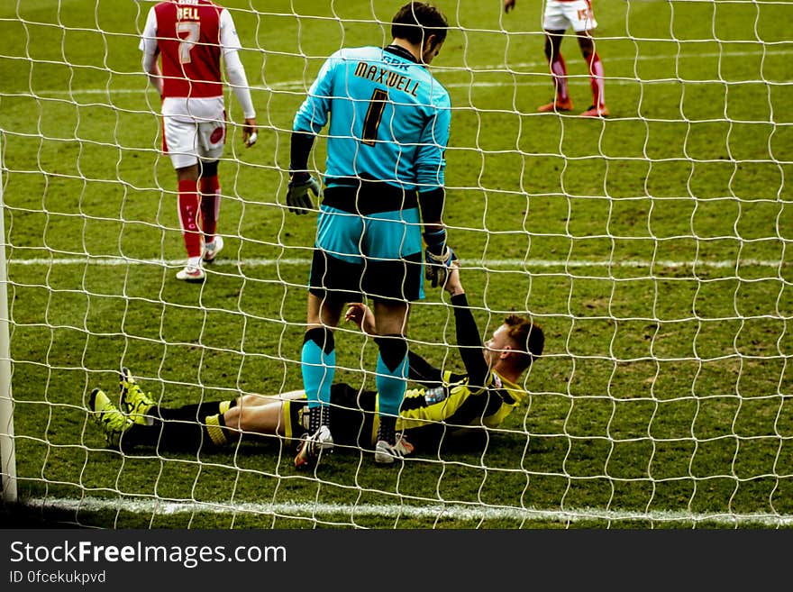 Soccer players standing in goal net during game on sunny day. Soccer players standing in goal net during game on sunny day.