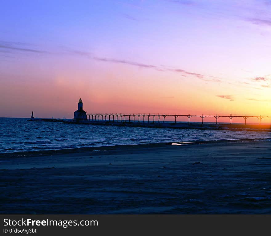 Silhouette of Gray Steel Bridge on Sea Shore during Sunset