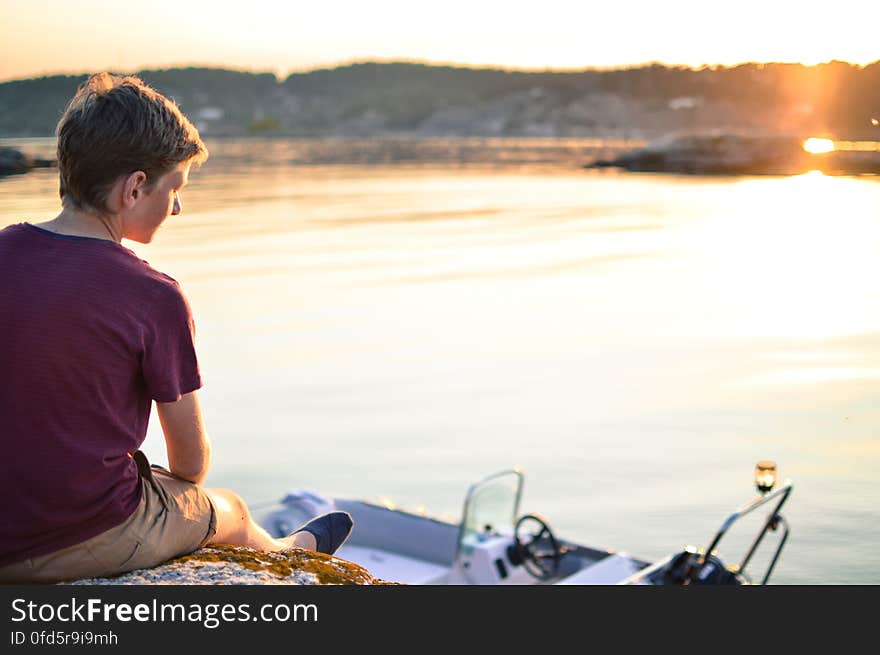 Man Sitting on Beach Against Sky during Sunset