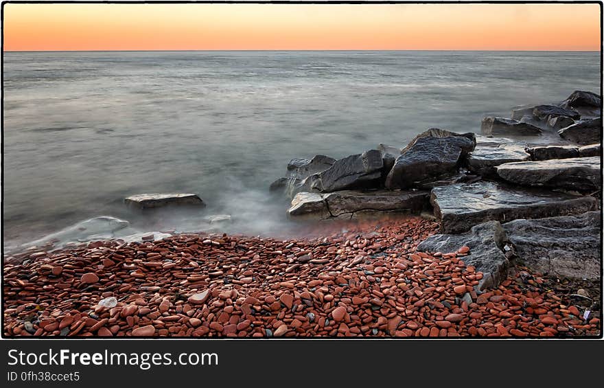 Sunset on the shore of Lake Ontario. The red &#x22;stones&#x22; are actually broken clay bricks and tiles. Sunset on the shore of Lake Ontario. The red &#x22;stones&#x22; are actually broken clay bricks and tiles.