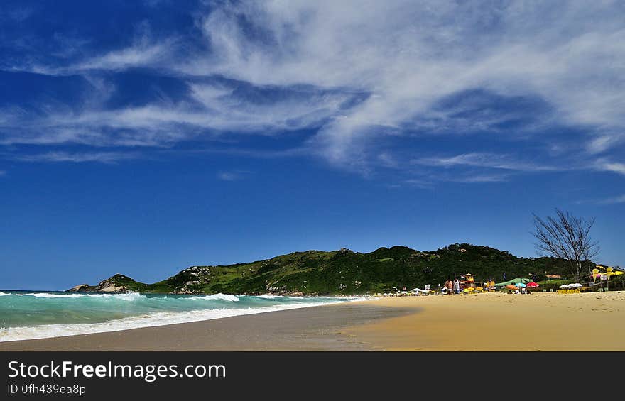 Green Mountain Near Sea Under White Clouds and Blue Sky