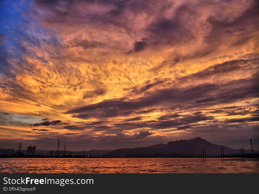 Sea and Silhouette of Mountain Under Orange Sky during Golden Hour