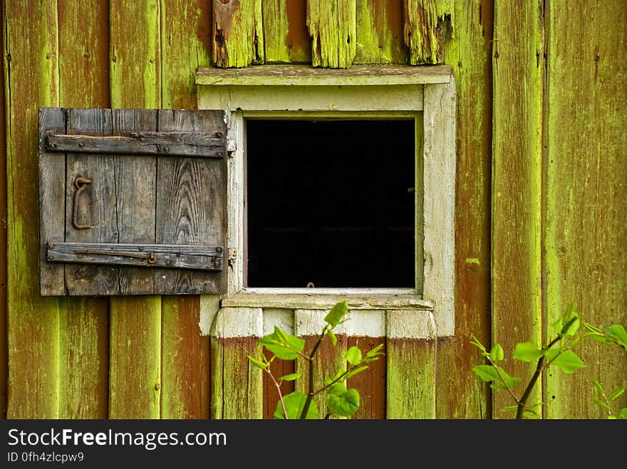 Closeup of old wooden building with small window and rough shutter (hinged door) to fit the opening during inclement weather. Closeup of old wooden building with small window and rough shutter (hinged door) to fit the opening during inclement weather.