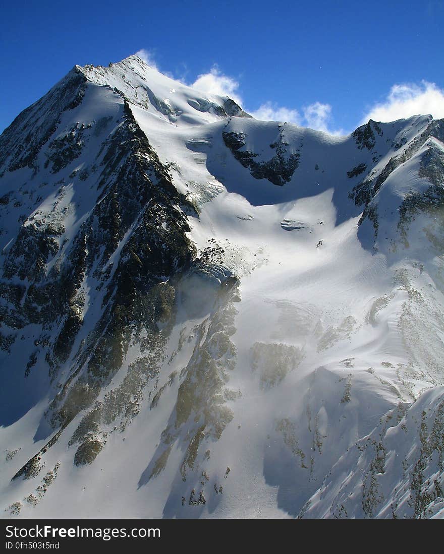 Snowy mountain range under blue skies.