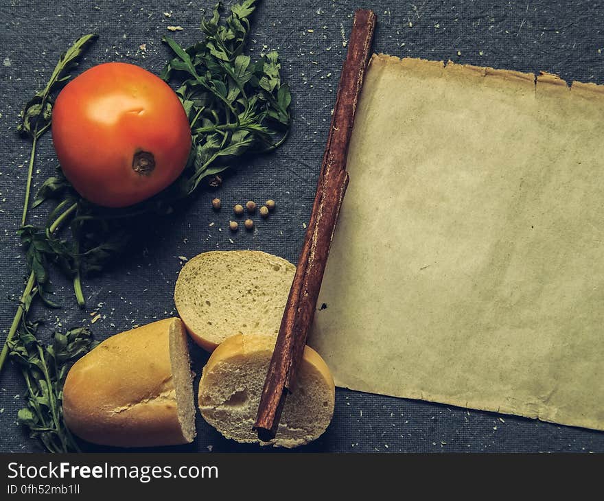 A rustic background with tomato, bread, herbs and an old parchment paper. A rustic background with tomato, bread, herbs and an old parchment paper.