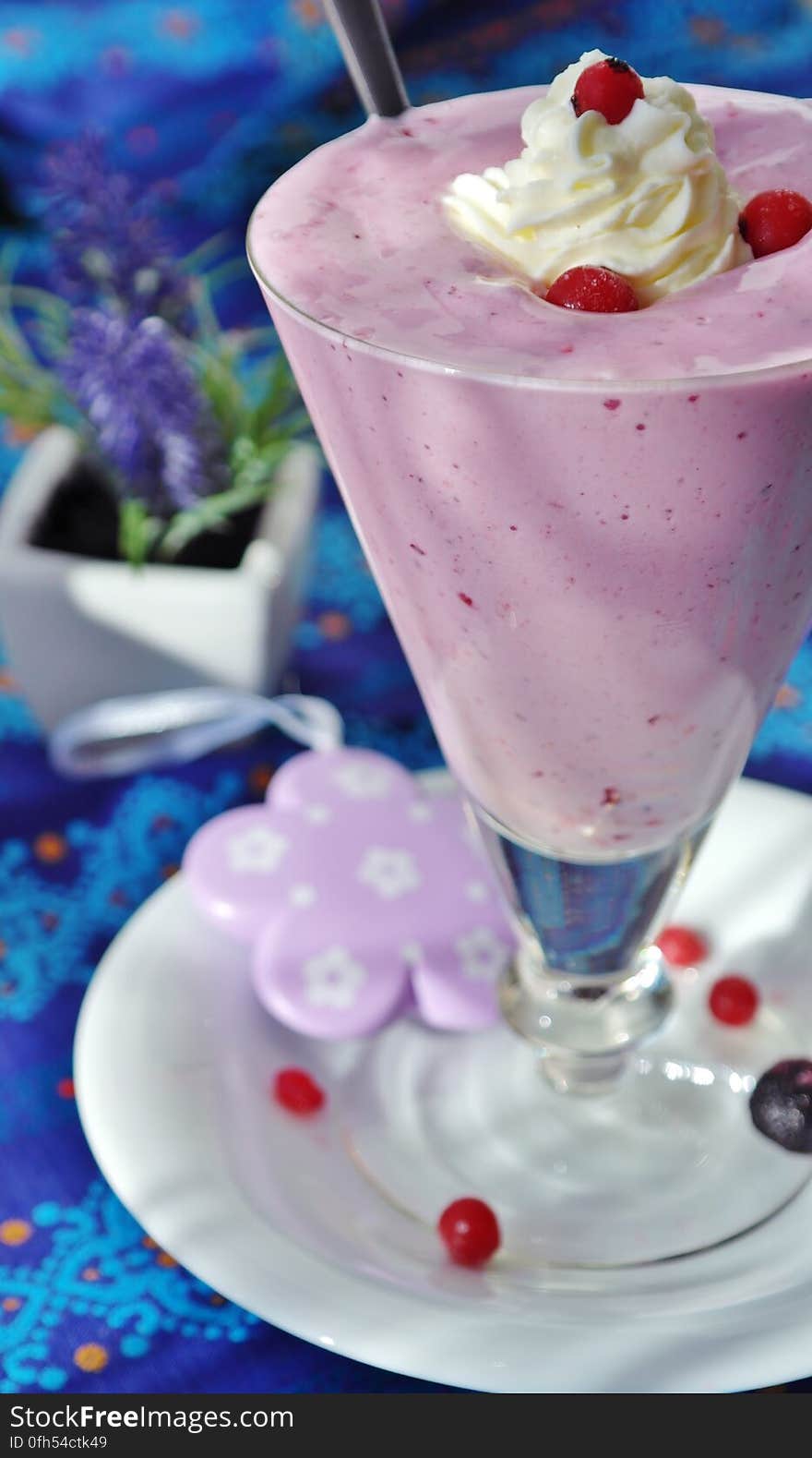 Strawberry milkshake in tall glass with berries and vanilla ice cream.