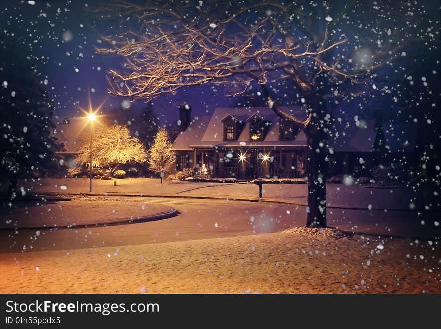 A residential house in snowy weather at night.