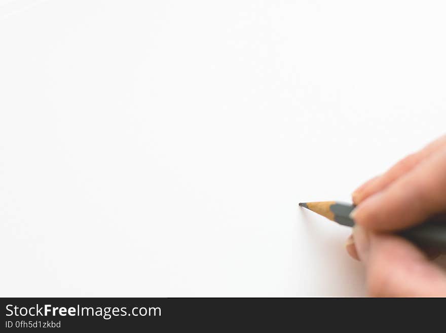 Close-up of Hand Holding Pencil over White Background