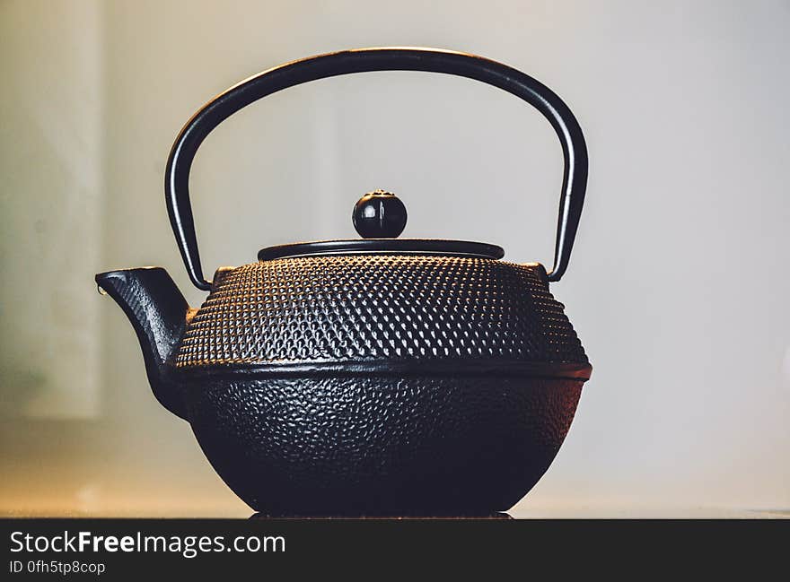 Side view of antique teapot with white wall in background.