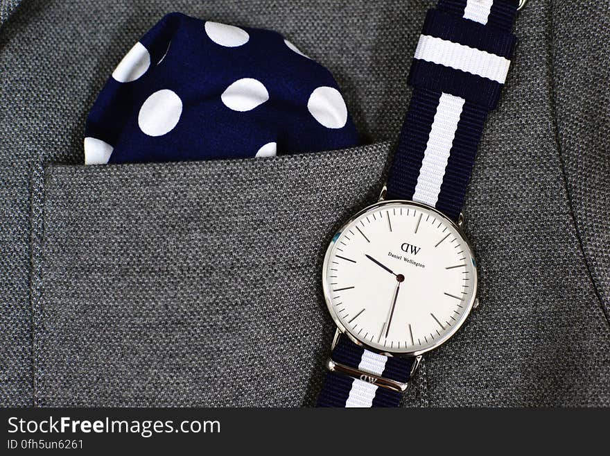 A gray suit with a polka dot pocket square and a Daniel Wellington wrist watch. A gray suit with a polka dot pocket square and a Daniel Wellington wrist watch.