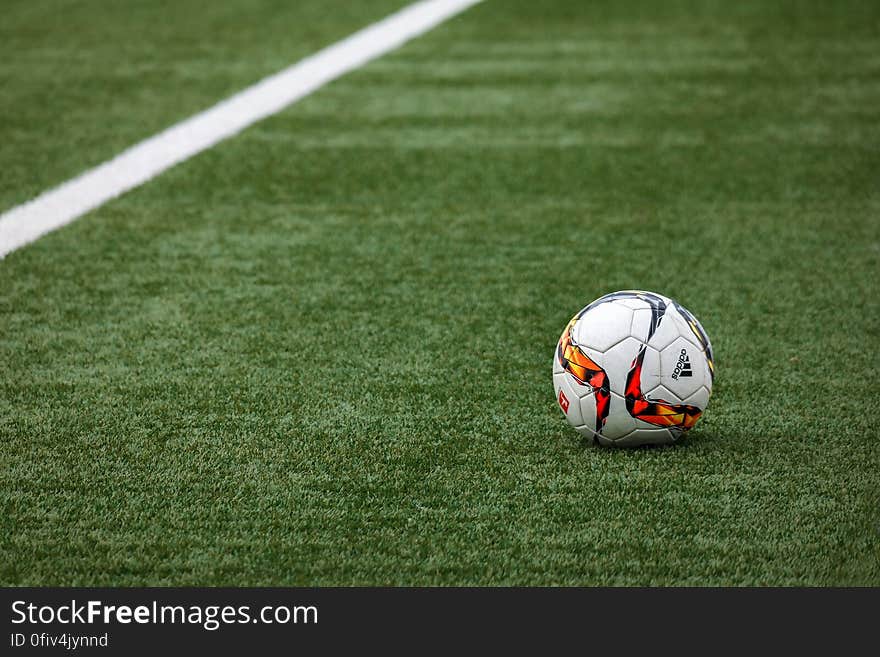 White official football with colorful decoration placed on green turf in stadium ready for match (or kick off). White official football with colorful decoration placed on green turf in stadium ready for match (or kick off).