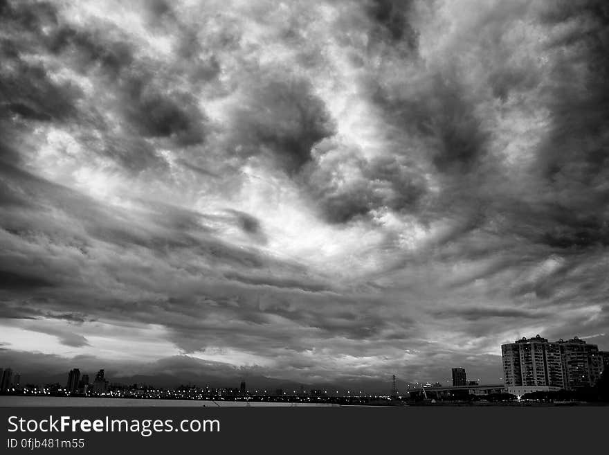 A black and white view of cloudy skies above a city. A black and white view of cloudy skies above a city.