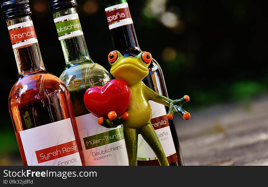 Green Frog With Red Heart Figurine Beside Glass Bottles