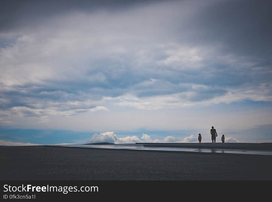 Silhouettes of father and children on an empty beach. Silhouettes of father and children on an empty beach.