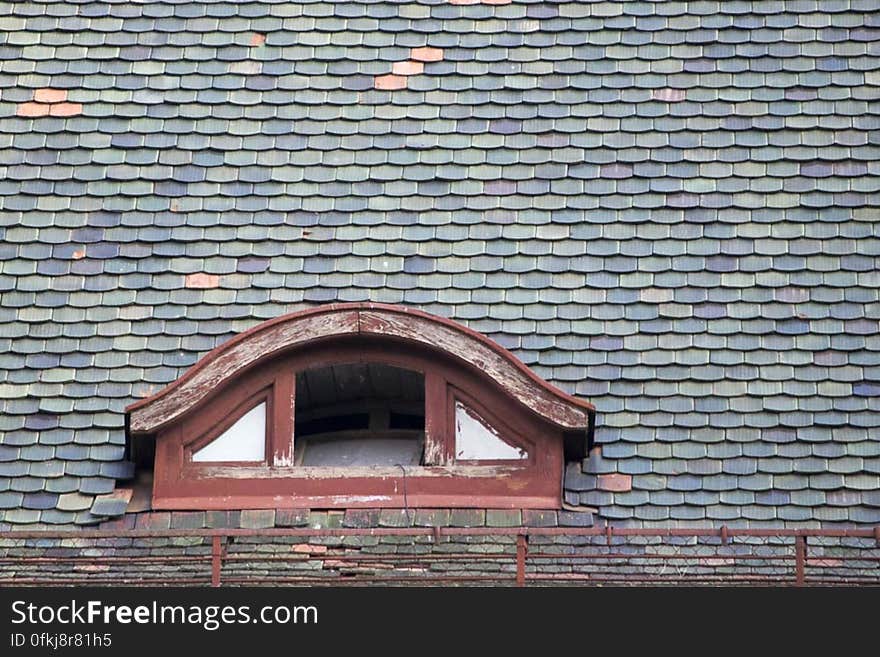 Photo of a semi round garret opening on a shingled roof.