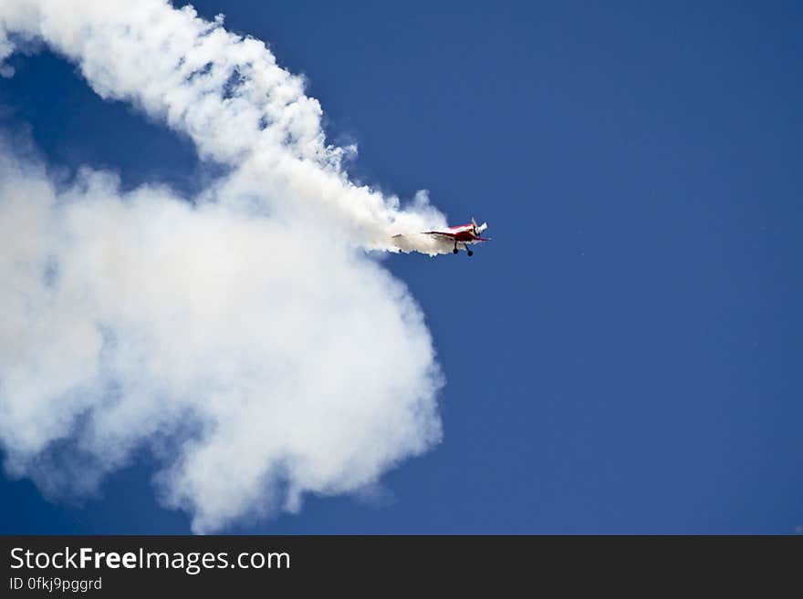 A low wing Sukhoi Su-31 monoplane covered in smoke after performing a loop. A low wing Sukhoi Su-31 monoplane covered in smoke after performing a loop.