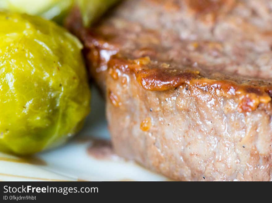 Medium rare beef steak with a side of buttered Brussels sprouts on a plate. Medium rare beef steak with a side of buttered Brussels sprouts on a plate.