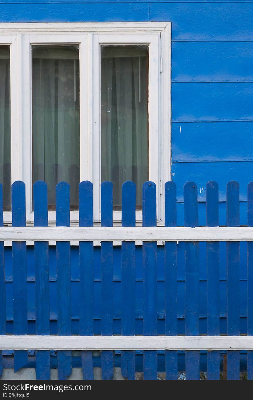 Country home painted in blue, with white window frames and matching fence.