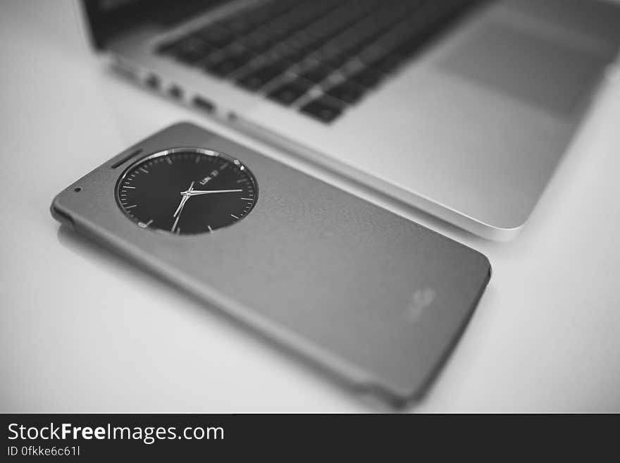 Closeup of modern clock on device next to open laptop, monochrome view. Closeup of modern clock on device next to open laptop, monochrome view.