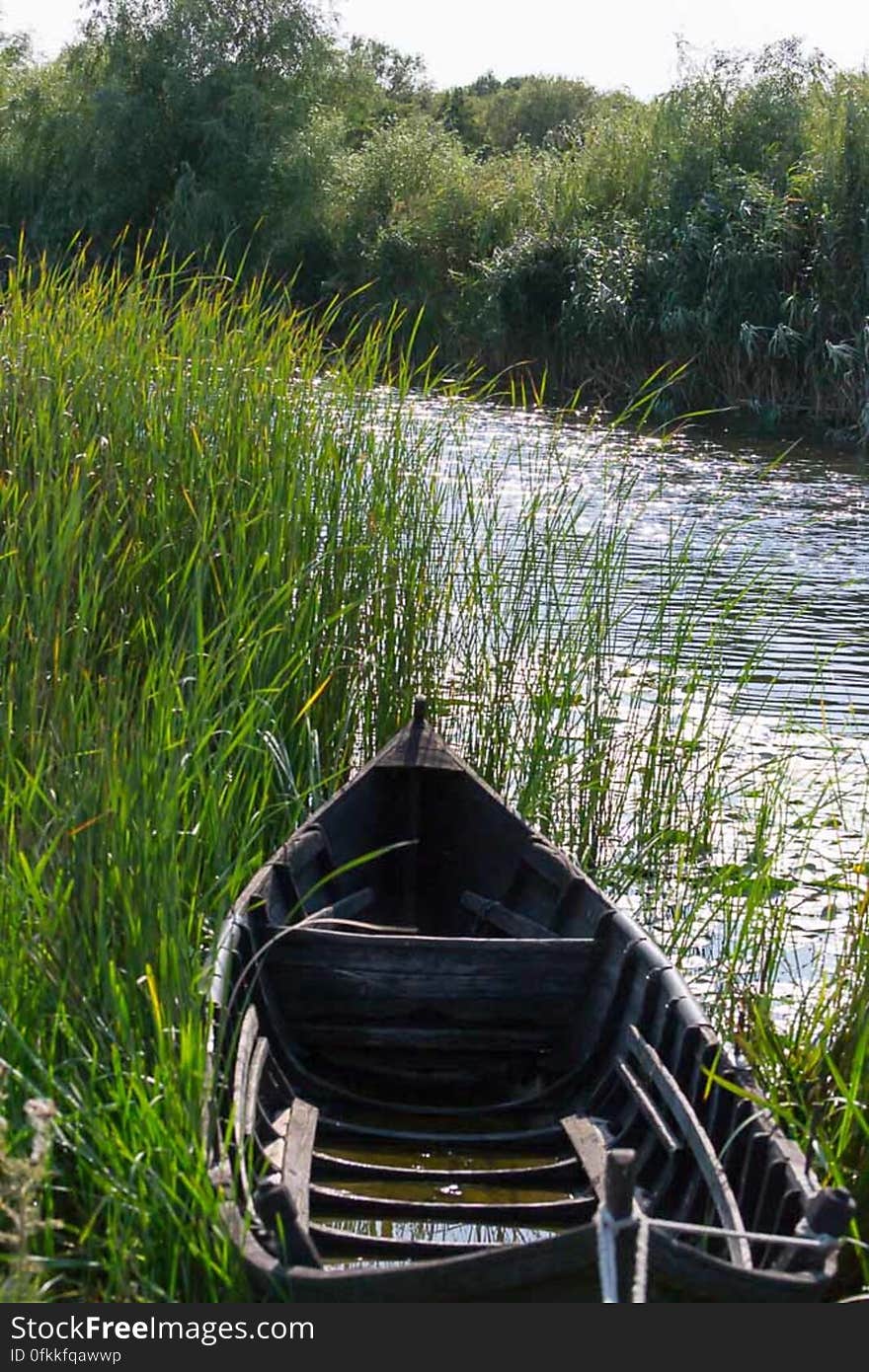 Traditional wooden boat tied up to shore by rope. Traditional wooden boat tied up to shore by rope.