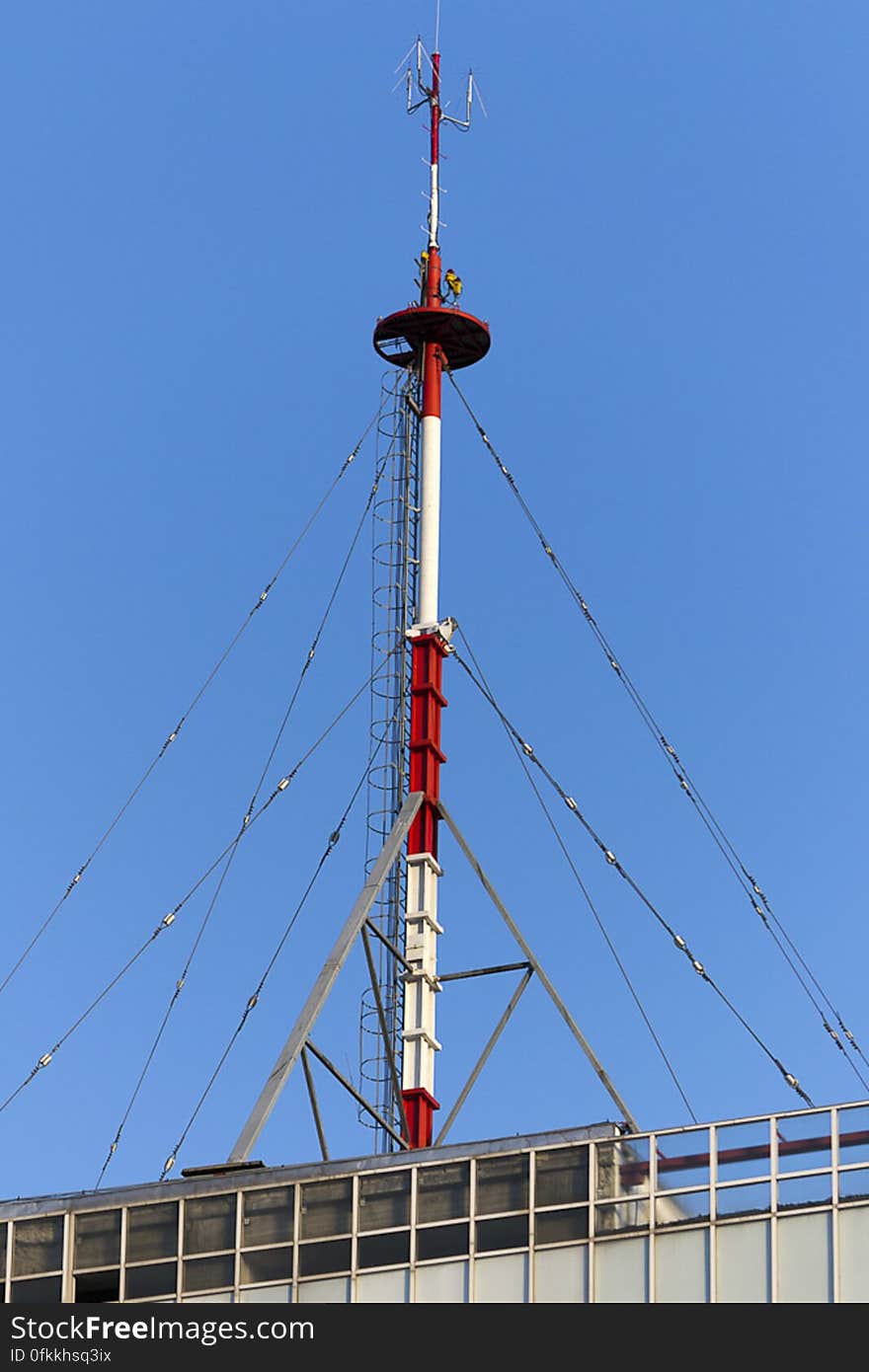 Transmitting antenna on top of a building secured by guy wires. Transmitting antenna on top of a building secured by guy wires.