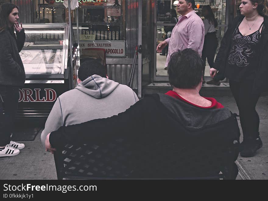 People walking on street and sitting on bench. People walking on street and sitting on bench.