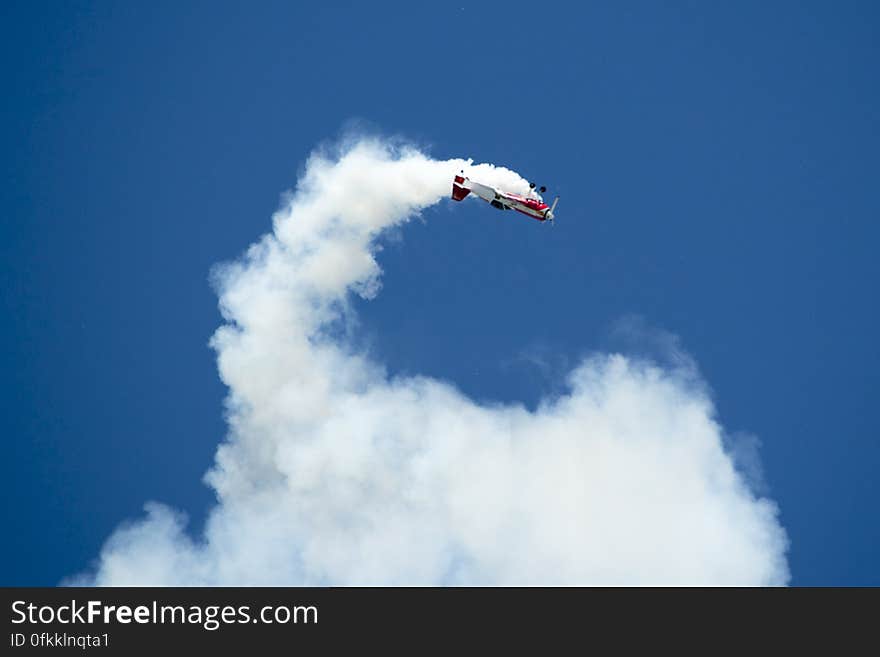 A russian Sukhoi Su-31 aerobatics aircraft performing an inside loop while leaving smoke traces.