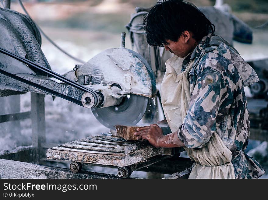 A carpenter in military uniform cutting wood using a circular saw. A carpenter in military uniform cutting wood using a circular saw.