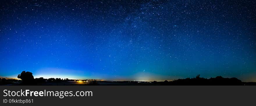 Starry night sky with silhouetted landscape.