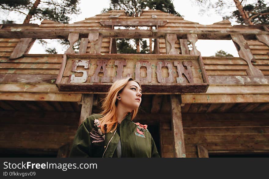 A woman standing in front of an old saloon. A woman standing in front of an old saloon.