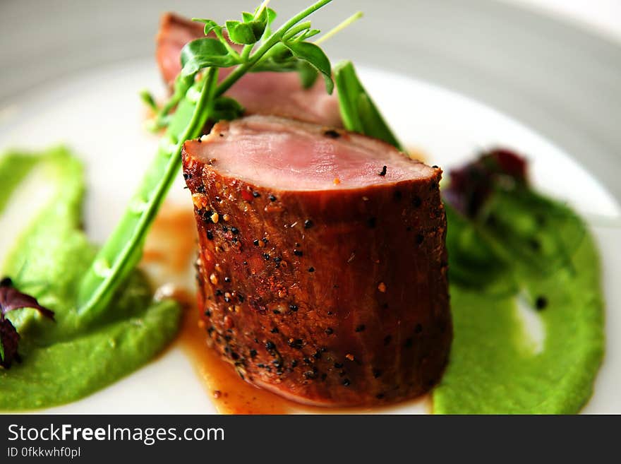 A plate with a fillet of meat and green pea puree. A plate with a fillet of meat and green pea puree.