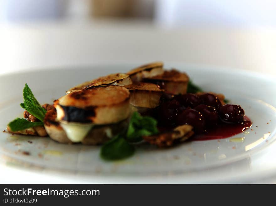 A plate of fried cheese with cherries and mint.