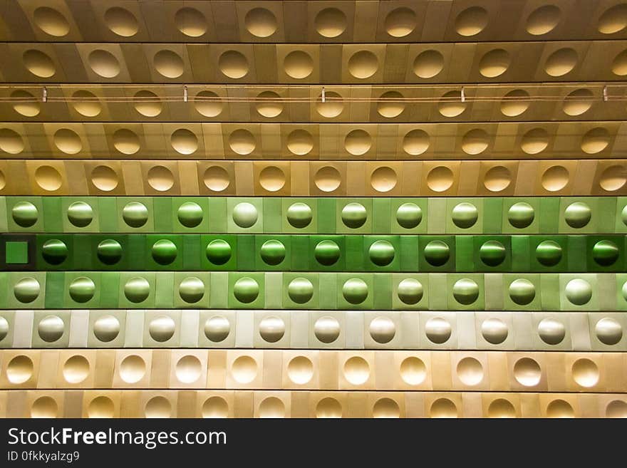 Metallic wall with circular shapes form a patter of different color shades in an metro station. Metallic wall with circular shapes form a patter of different color shades in an metro station.