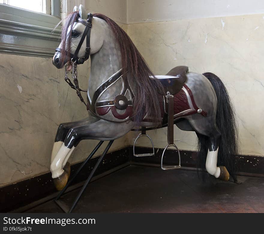 Wooden horse toy with reins, seat and stirrups.