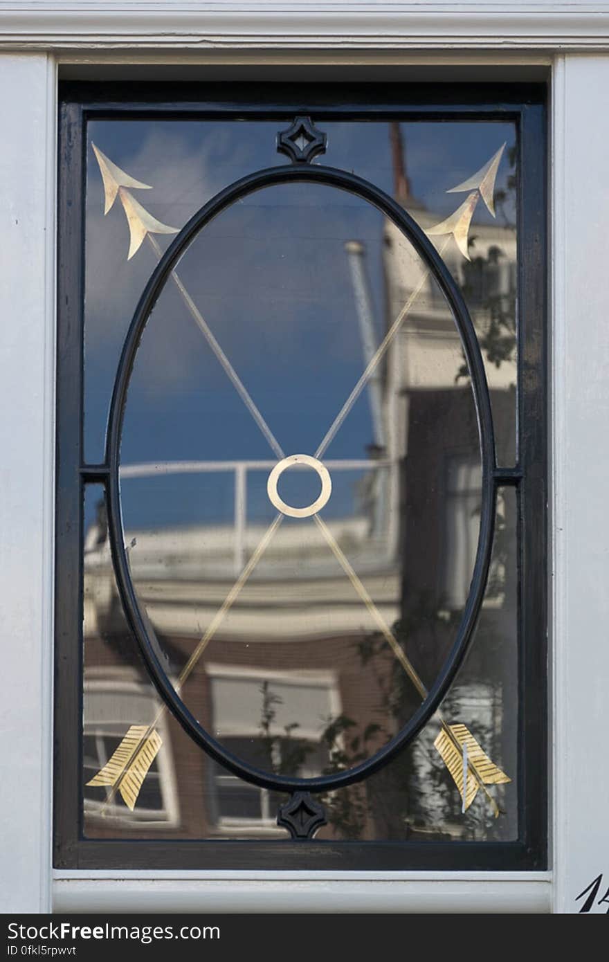 House window with cast iron frame and ornated with two gilded arrows with double points. House window with cast iron frame and ornated with two gilded arrows with double points